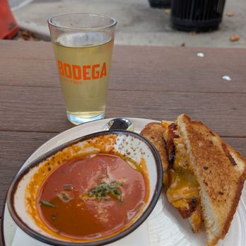 Bodega signature dishes  Various Grilled Cheese Sandwiches (e.g., The Bodega Classic, The Mac & Cheese Grilled Cheese), Tomato Soup, Happy Hour specials.